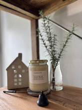 Desert Bloom luxury soy candle in glass jar with gold lid, styled on wood shelf with greenery and decor