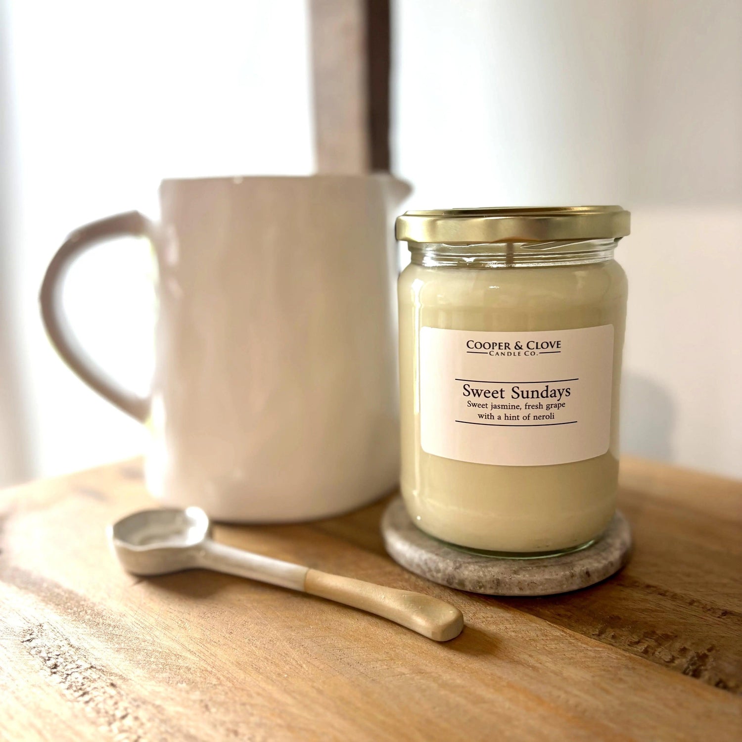 Sweet Sundays soy candle with jasmine & grape scent, luxury home fragrance in glass jar beside ceramic mug