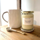 Sweet Sundays soy candle with jasmine & grape scent, luxury home fragrance in glass jar beside ceramic mug