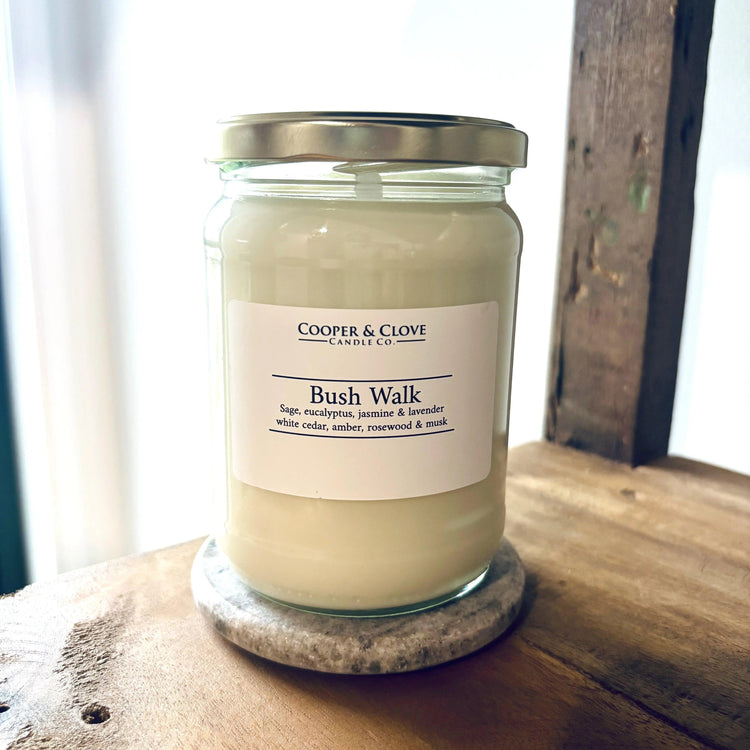 Bush Walk soy candle in glass jar with silver lid, featuring sage, eucalyptus & lavender scents, on wooden surface