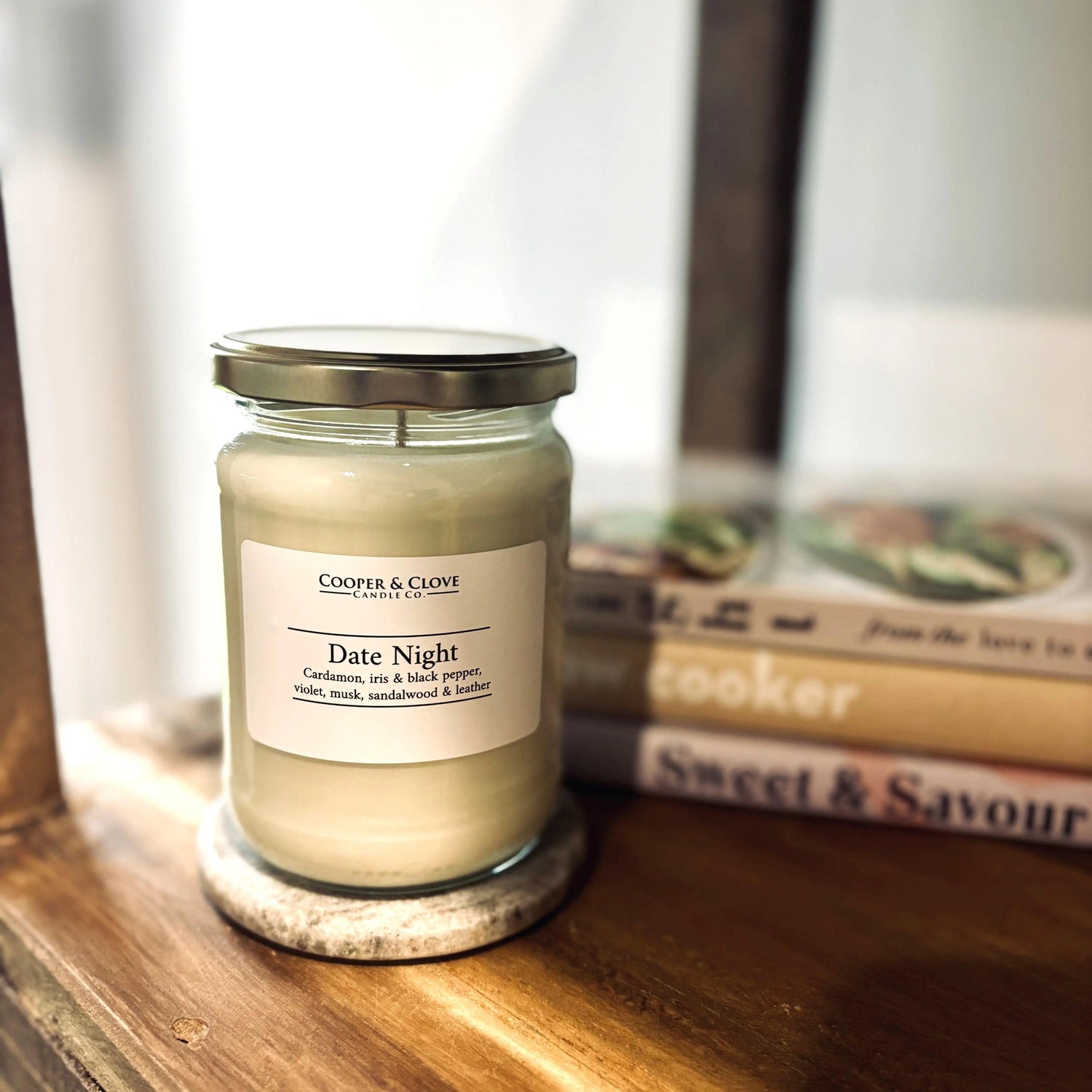Date Night scented soy candle in glass jar with metal lid, placed on wooden shelf beside books, luxury home fragrance