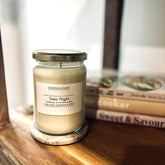 Date Night scented soy candle in glass jar with metal lid, placed on wooden shelf beside books, luxury home fragrance